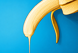 Peeled banana with dripping liquid on a blue background, used as a visual metaphor in discussions about oral sexual health and sore throat concerns.